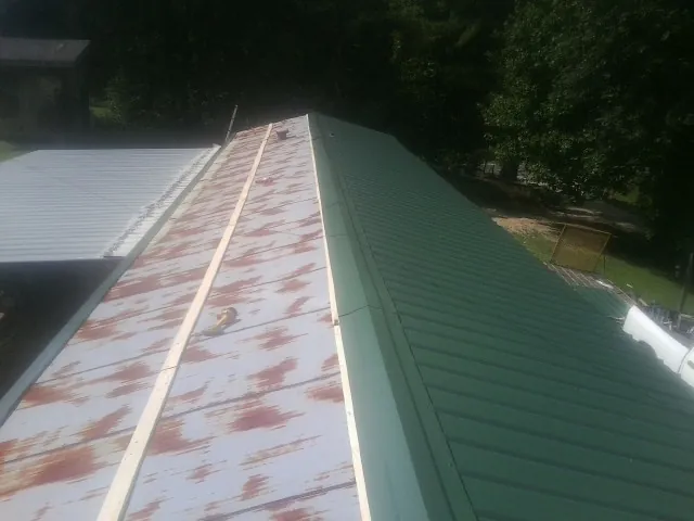 Old rusted panels beside newly installed green metal roofing — Wind Damage Roof Repair by Roofing Brothers in Liverpool
